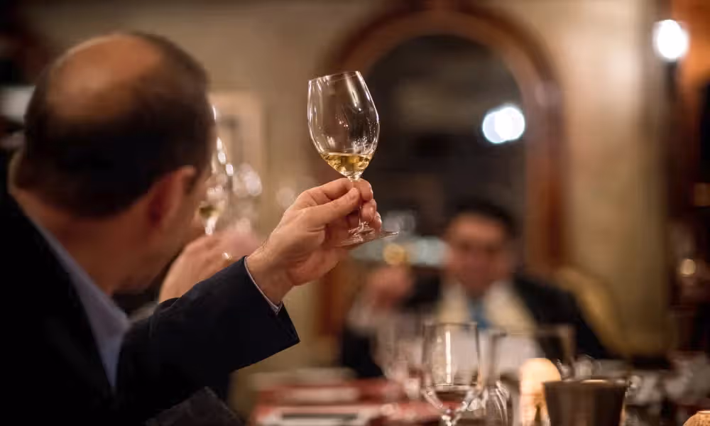 Man holding up glass filled with white wine.